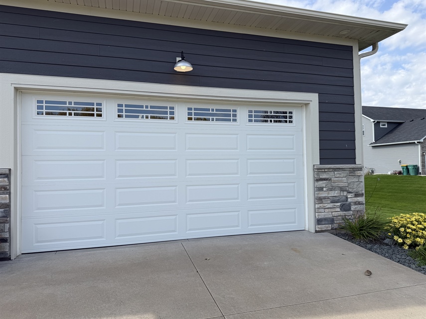 Close-up of a newly installed white insulated garage door with decorative windows in Ham Lake, MN.