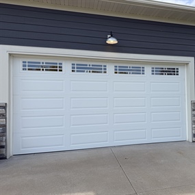 Close-up of a newly installed white insulated garage door with decorative windows in Ham Lake, MN.