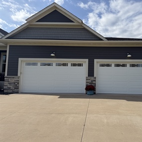 Completed insulated garage door installation featuring two white garage doors on a home in Ham Lake, MN.