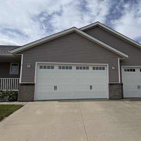 Insulated white carriage-style garage door installed on a residential home in New Ulm, MN.