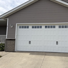 Completed carriage-style garage door installation with decorative windows and classic panel detailing in New Ulm, MN.